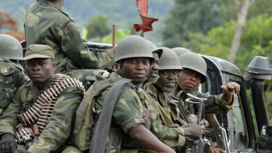 Democratic Republic of Congo army soldiers sit at the back of a pick-up truck as they head towards the Mbuzi hilltop