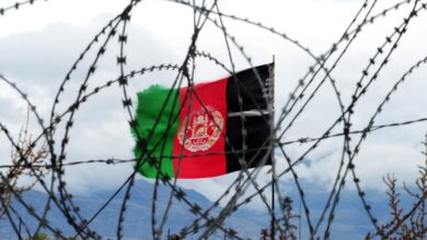 Afghan flag behind barbed wire.