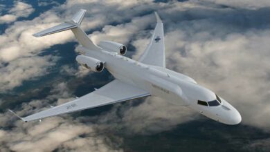 A white Bombardier Global 6500 plane soars above the clouds. It has light blue stripes painted on the edges of its wings and tail. The right side of its body, as well as its right wing, has Hangul (Korean alphabet) characters painted on it.