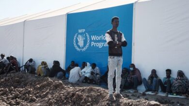 Ethiopian refugees wait for distribution of aid next to a warehouse erected by the World Food Programme at Um Raquba refugee camp in Gedaref, eastern Sudan