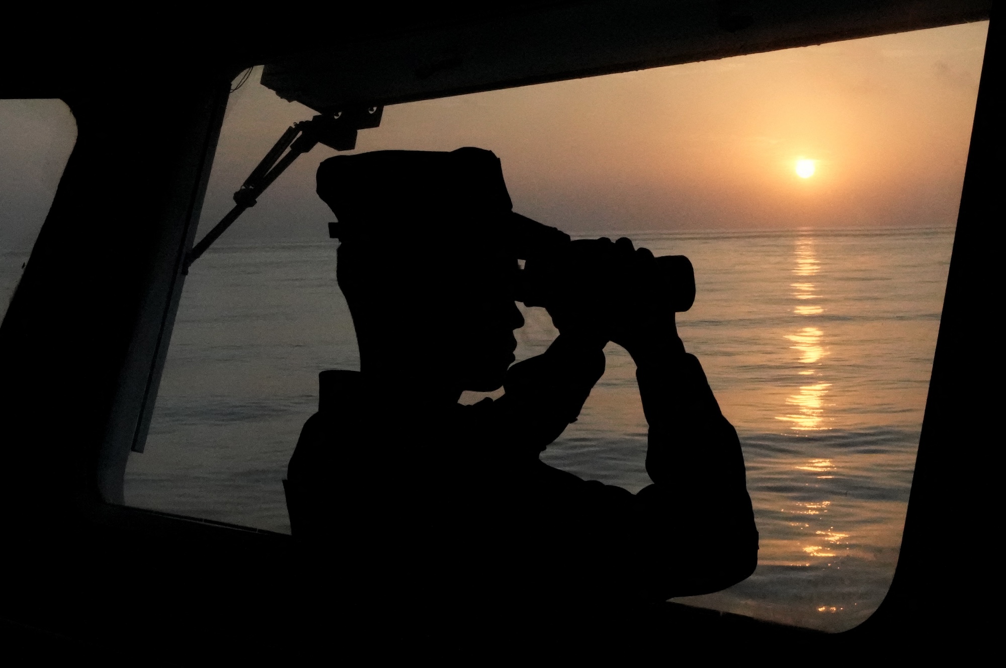 A law enforcer observes on the vessel "China Coast Guard (CCG) 3502" in the South China Sea, May 12, 2024