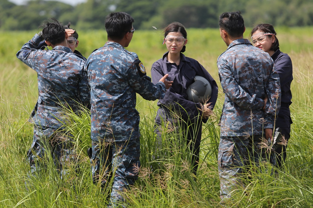 Three female student pilots from the Royal Thai Air Force listening to their instructors on the field