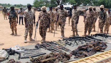 Military troops inspect arms and ammunitions recovered from Boko Haram jihadists.