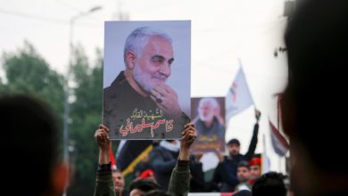 Mourners hold up pictures of General Qassem Soleimani at his funeral in January 2020.