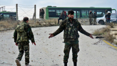 A Syrian soldier gestures during the evacuation of insurgents from a rebel-held area of Aleppo toward rebel-held territory in the west of Aleppo province