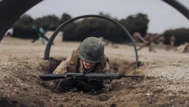 A US Marine Corps recruit crawls under an obstacle on the bayonet assault course at Marine Corps Recruit Depot San Diego, California